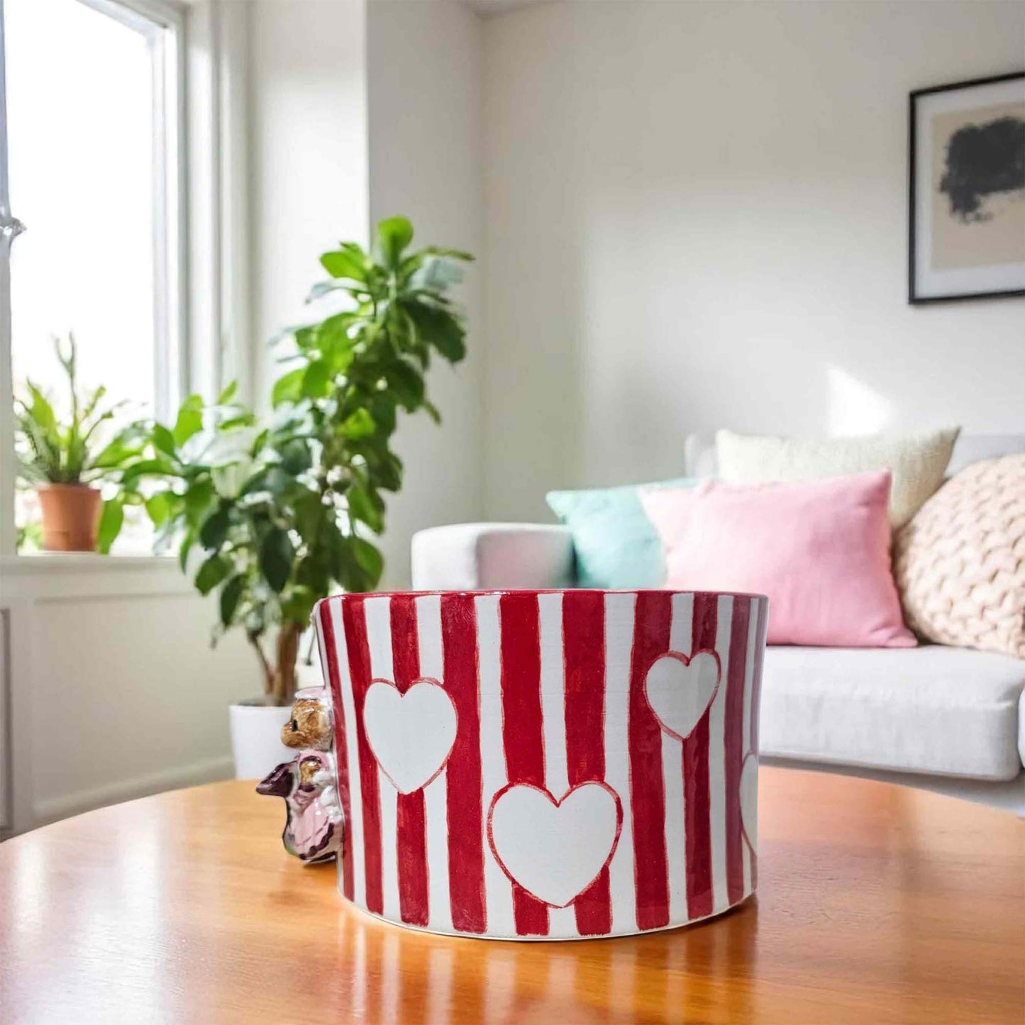 Red and white striped paper towel holder with heart designs on a wooden floor in a living room.