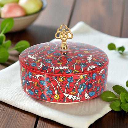 Decorative red sugar bowl with floral patterns on a white napkin