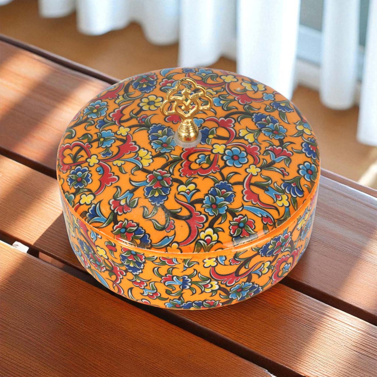 Decorative sugar bowl with colorful floral patterns on a wooden surface