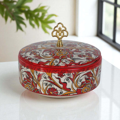 Decorative sugar bowl with intricate patterns and a gold lid on a white surface.