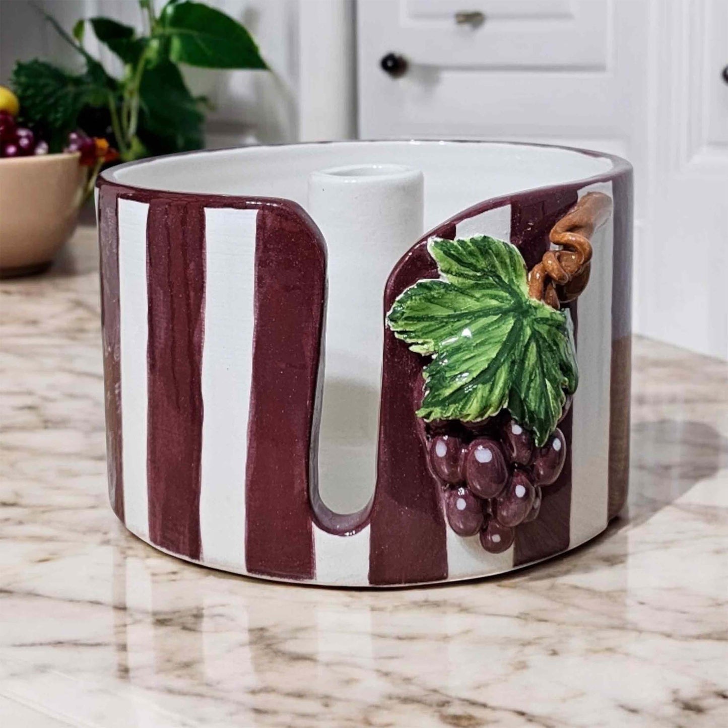 Ceramic paper towel holder with grape design on a marble countertop
