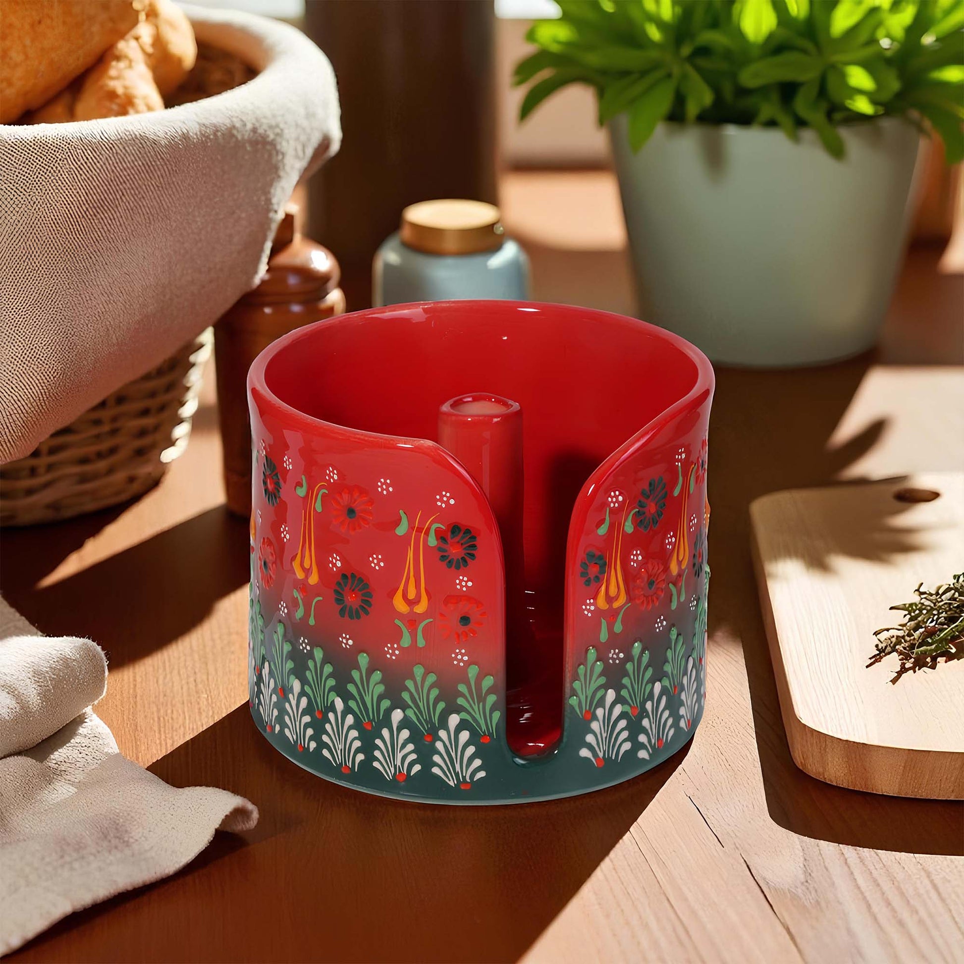 Red ceramic paper towel holder with floral patterns on a wooden surface