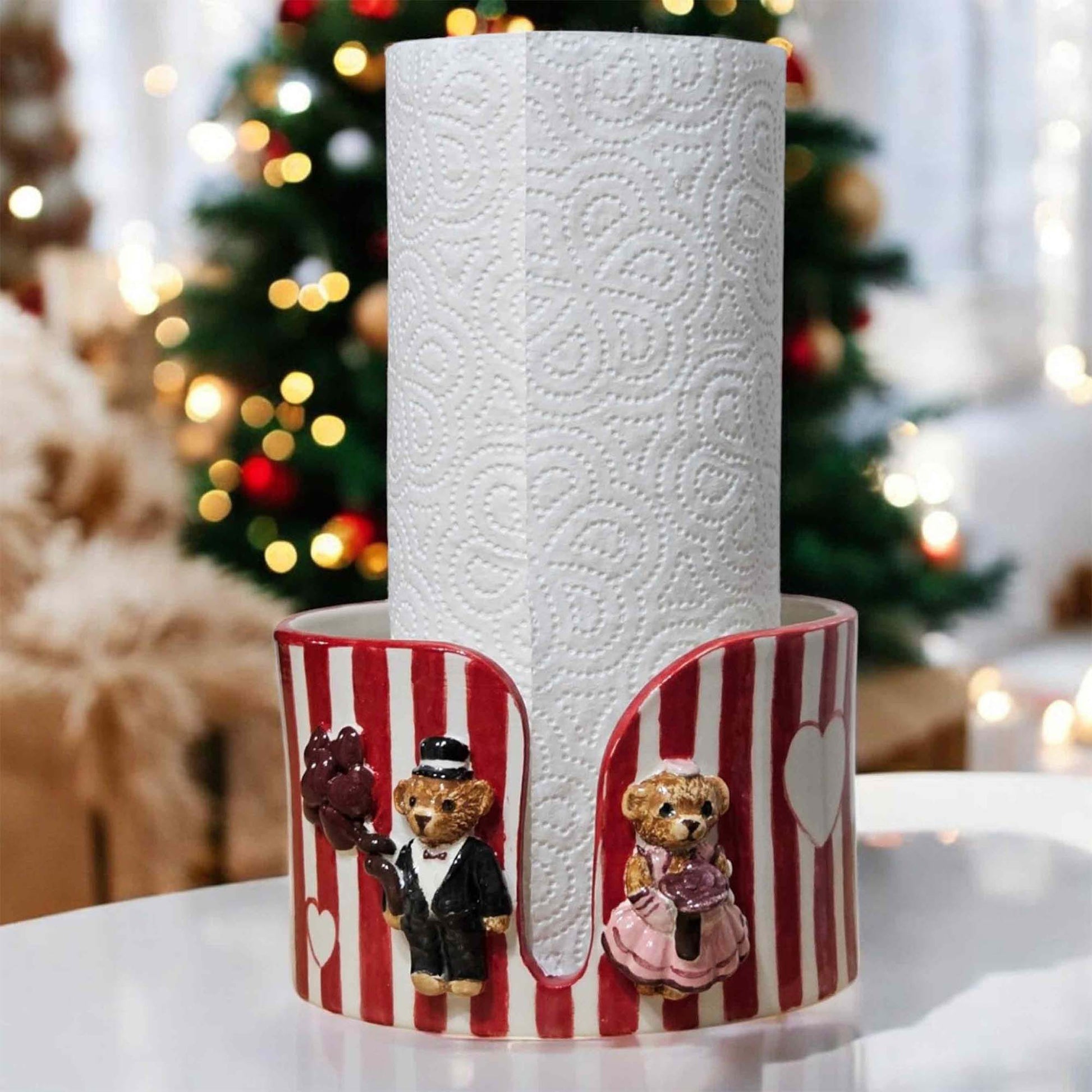 Decorative paper towel holder with teddy bears in front of a Christmas tree.