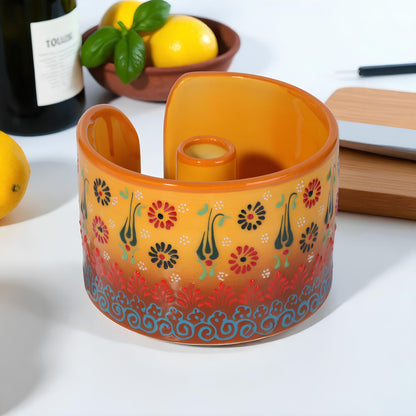 Decorative orange paper towel holder with floral patterns on a white surface