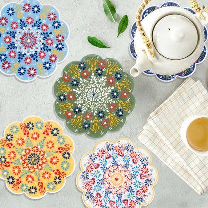 Colorful floral trivets on a gray surface with a teacup and leaves.