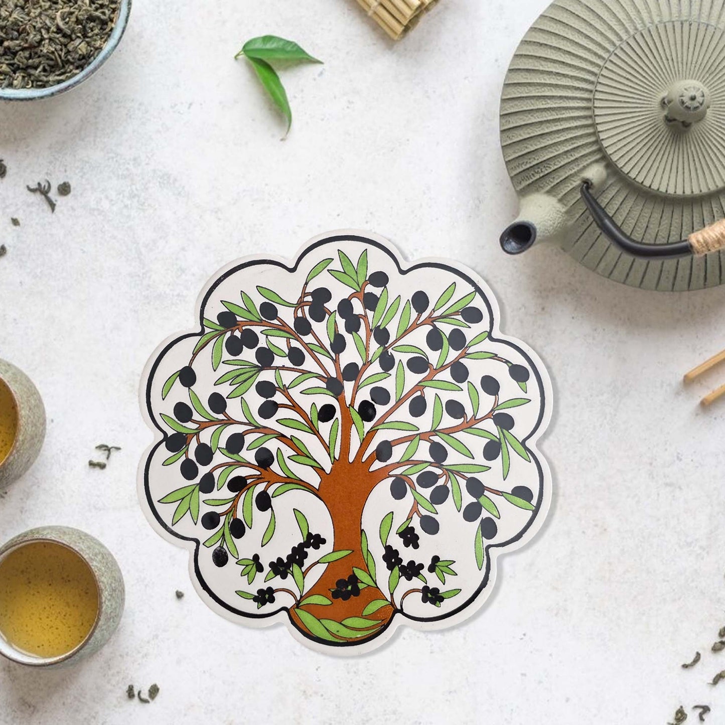 Decorative trivet with a tree design on a tea-themed surface