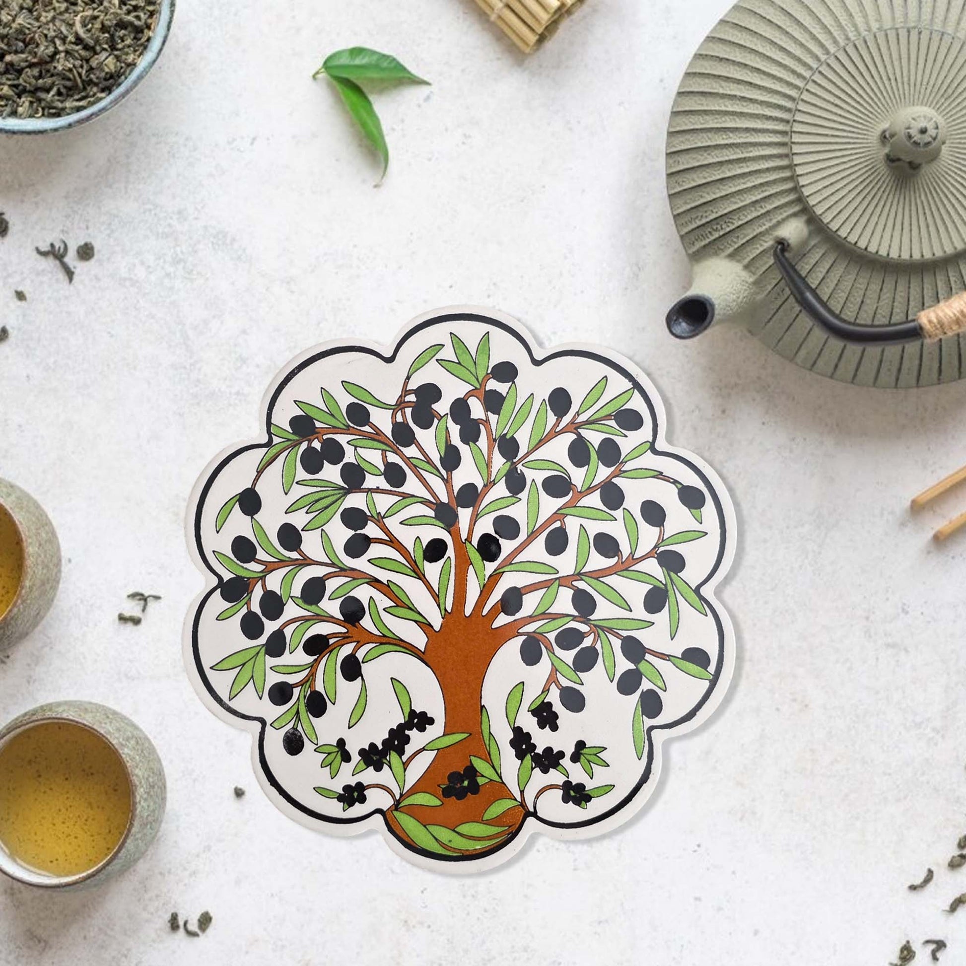 Decorative trivet with a tree design on a tea-themed surface