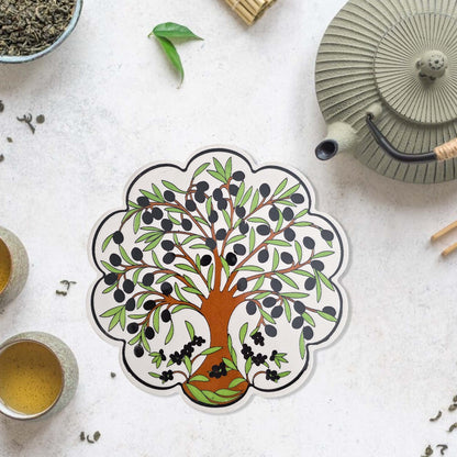 Decorative trivet with a tree design on a tea-themed surface
