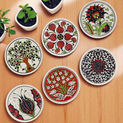 Set of decorative ceramic coasters with floral and abstract designs on a wooden surface.