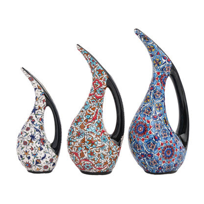A set of three hand-painted ceramic ewers with Ottoman floral patterns and glossy black handles.