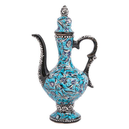 A hand-painted ceramic ewer with a turquoise base and black and white floral accents, featuring a curving spout and sculptural handle.