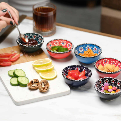Colorful bowls with snacks on a table with a plate of sliced cucumbers, tomatoes, and lemon.