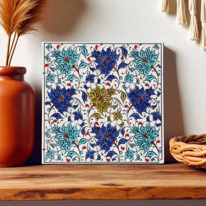 Decorative ceramic tile with floral pattern on a wooden surface with decorative items.