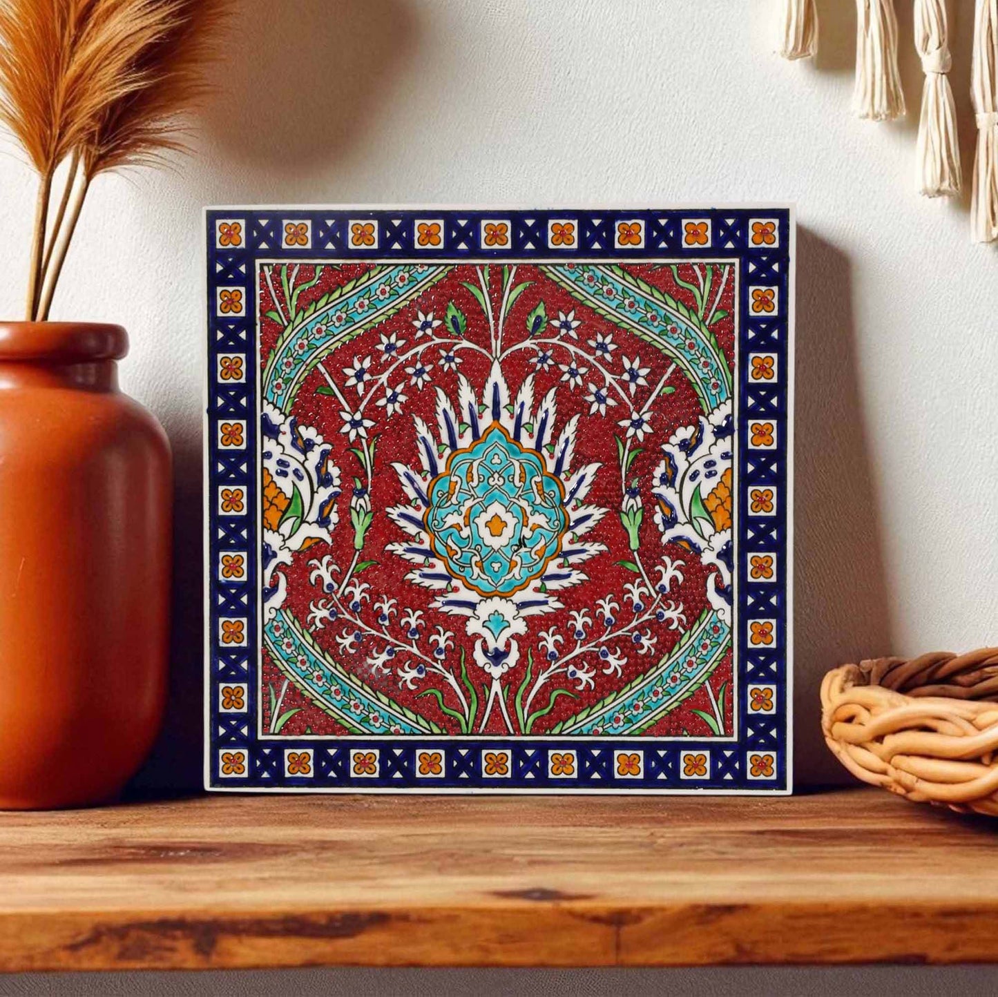 Decorative ceramic tile with intricate patterns on a wooden shelf.