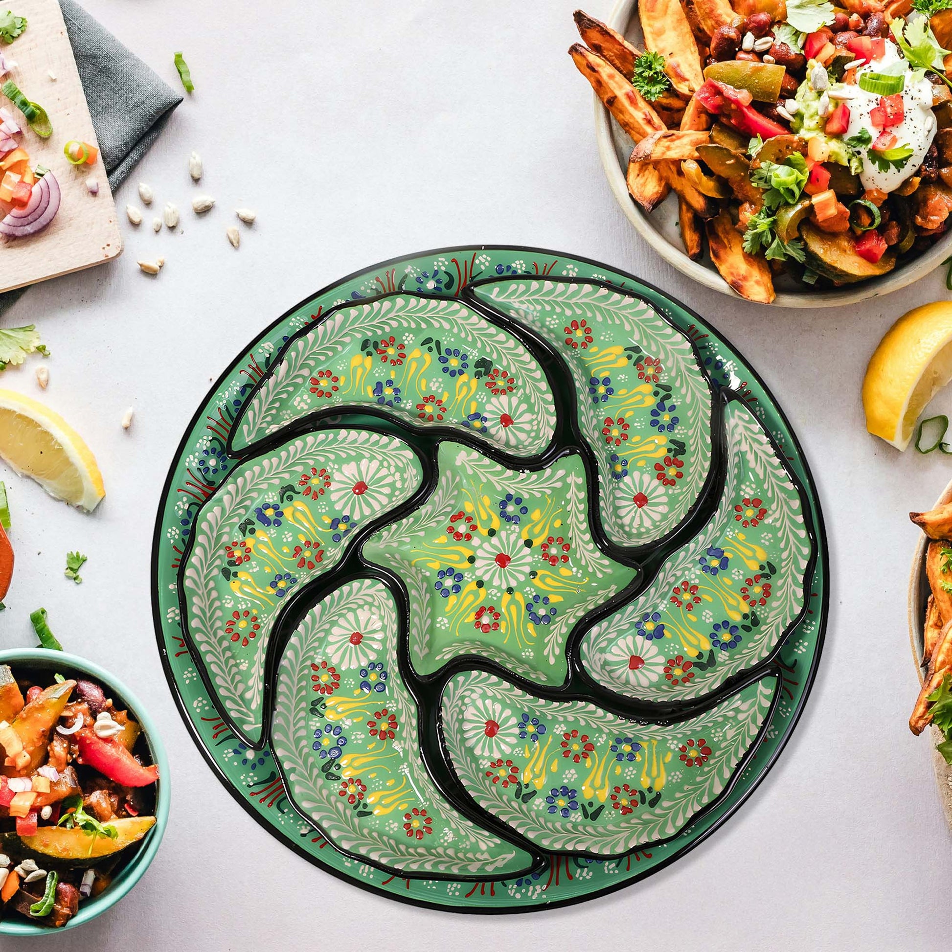 Decorative green snack serving tray set with floral patterns on a table with food.
