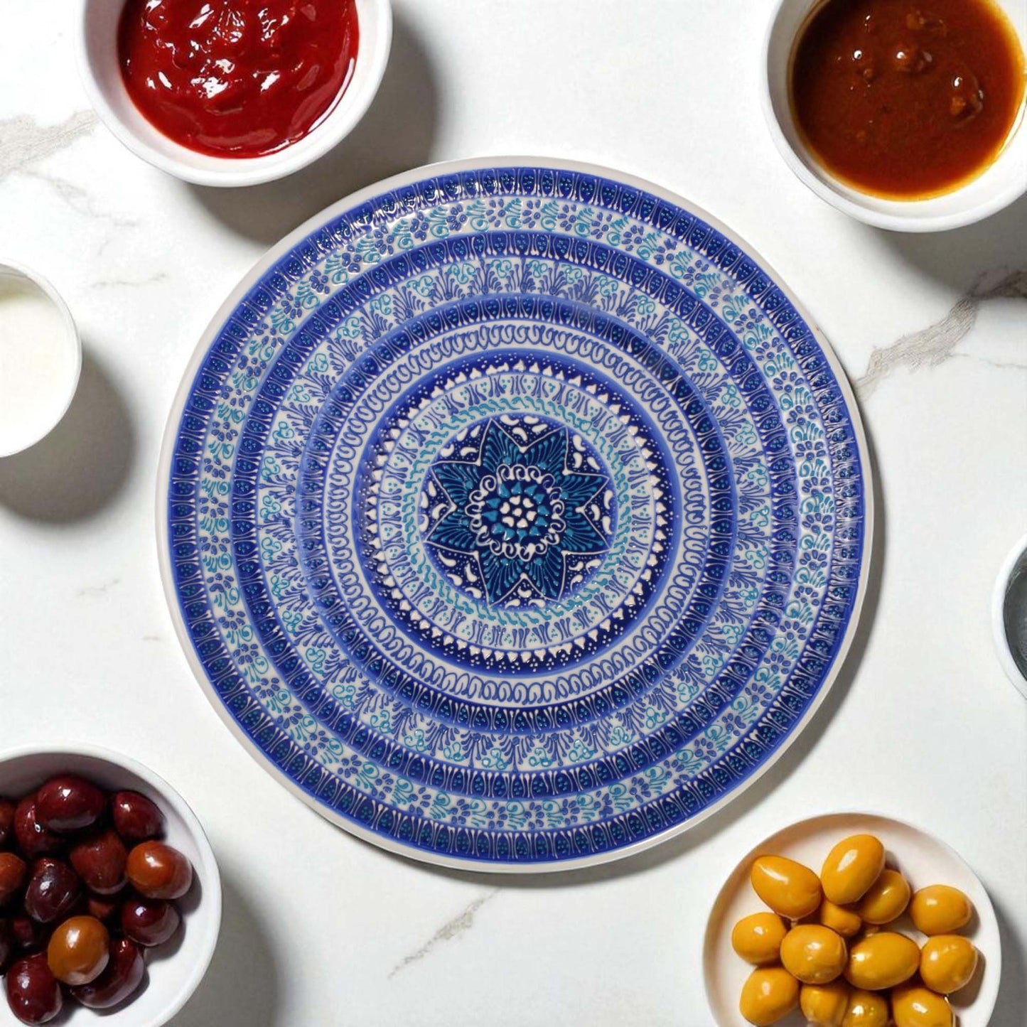 Decorative blue and white plate with a geometric pattern on a marble surface with small bowls of condiments.
