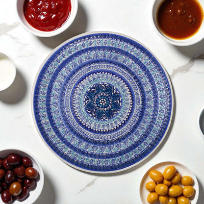 Decorative blue and white plate with a geometric pattern on a marble surface with small bowls of condiments.