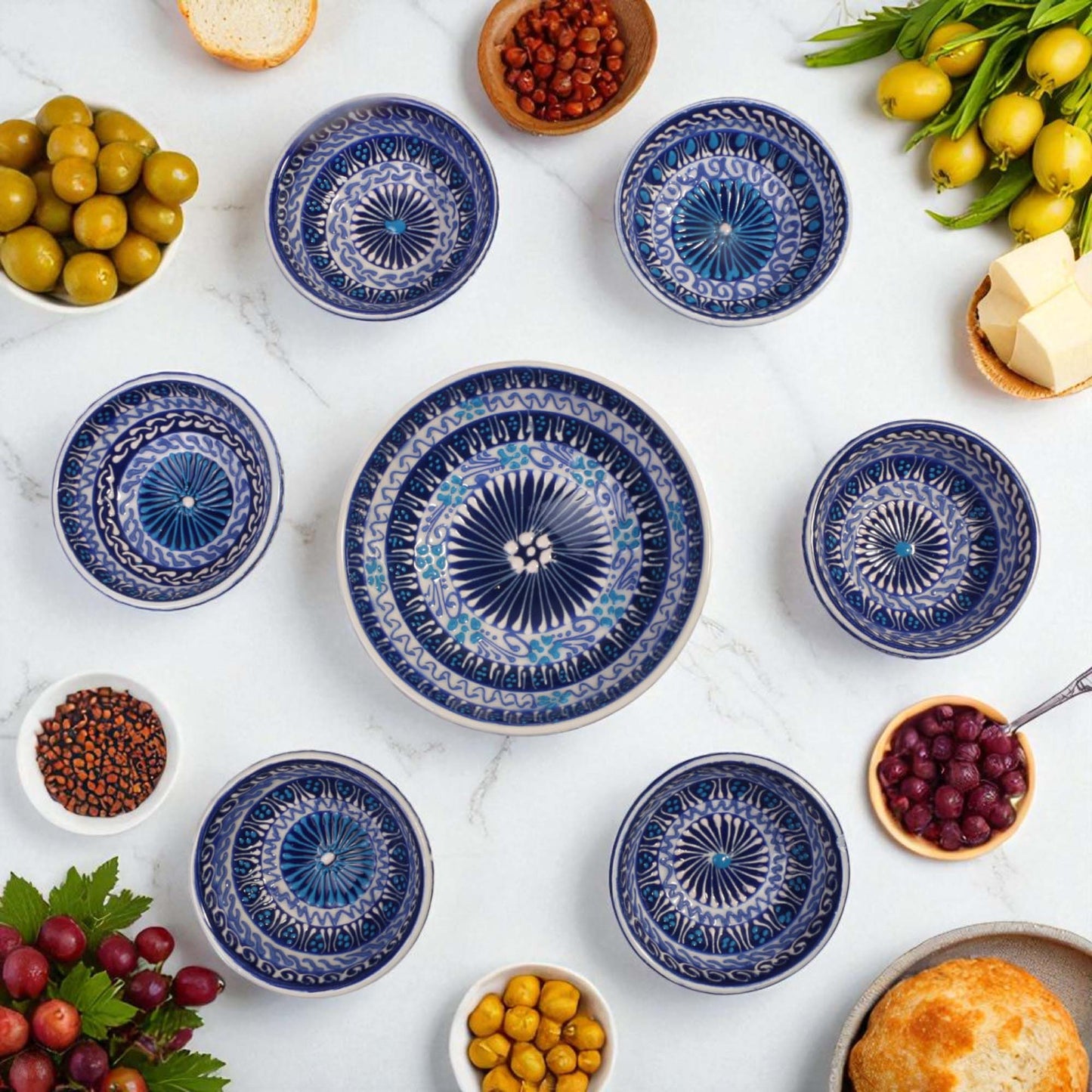 Set of blue ceramic plates with decorative patterns on a white surface with food items around.