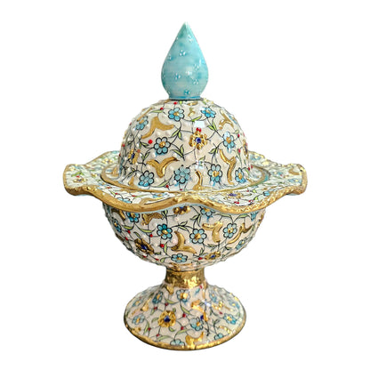 Decorative sugar bowl with floral patterns and a blue top on a white background