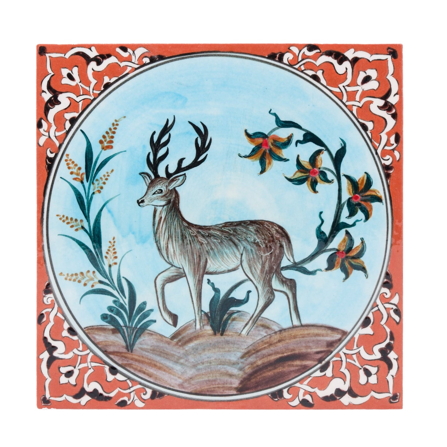 A handmade ceramic tile featuring a deer in a natural landscape with stylized plants and floral accents, with a terracotta border.