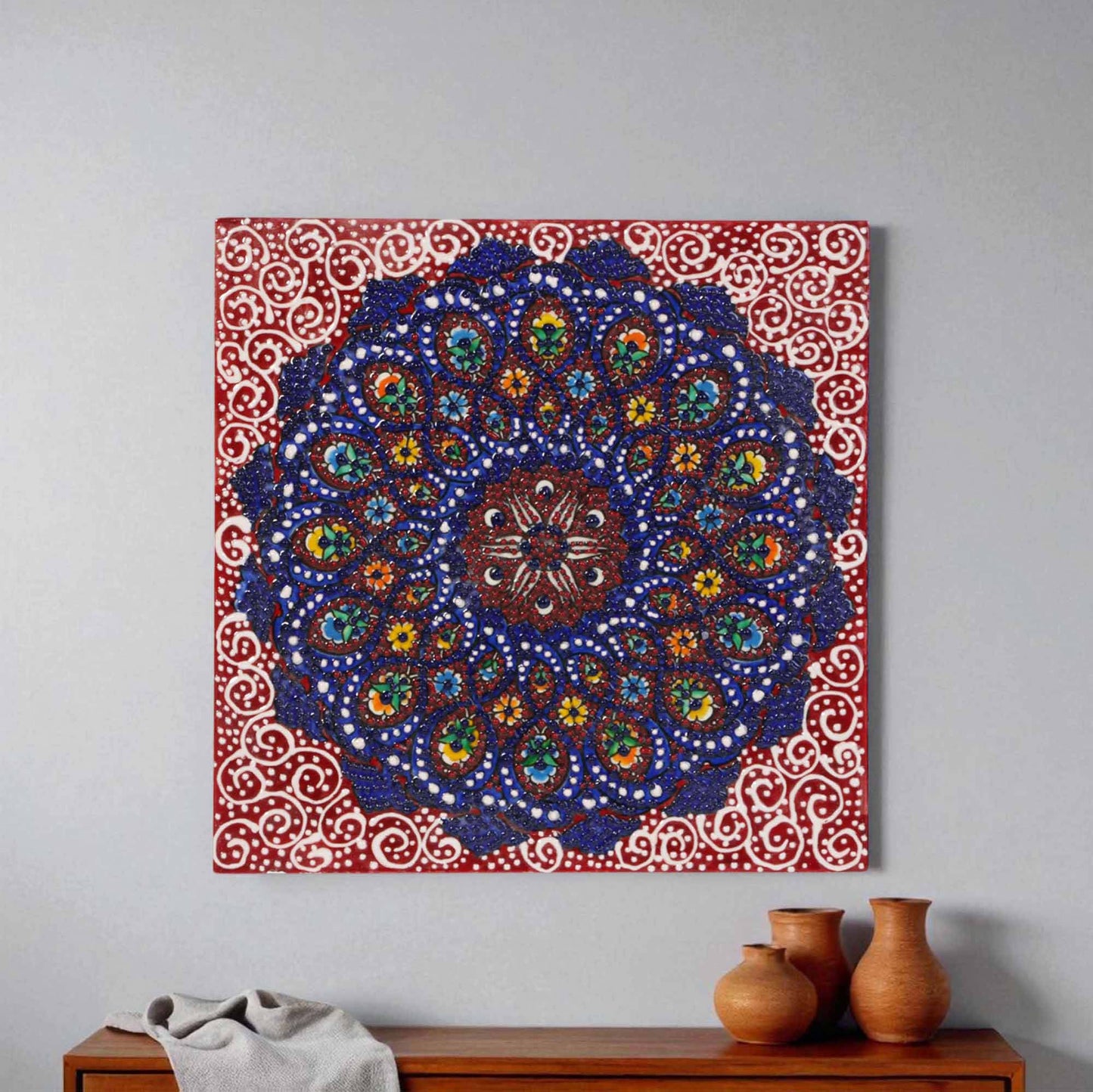 Decorative ceramic tile wall art with a colorful mandala design on a plain wall.