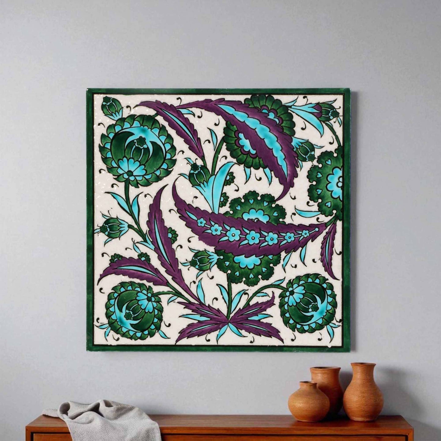 Decorative ceramic tile with floral pattern in green and purple on a white background, framed in green.