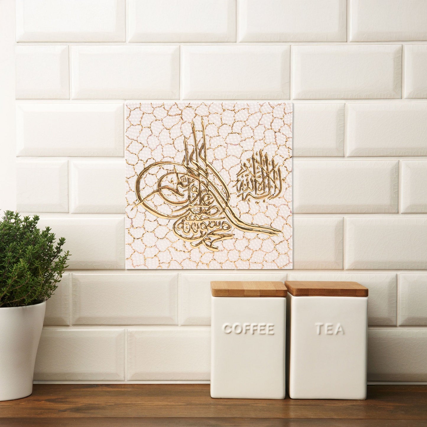 Decorative Arabic calligraphy ceramic tile on a white tiled wall with kitchen canisters.