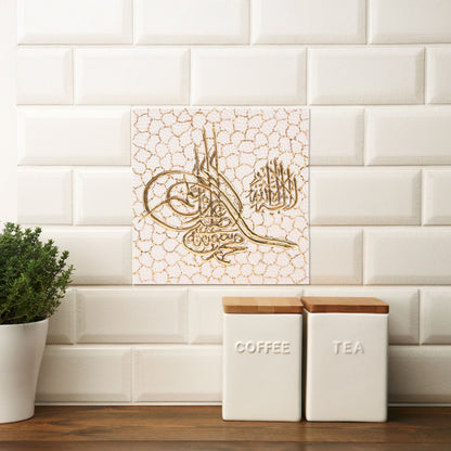 Decorative Arabic calligraphy ceramic tile on a white tiled wall with kitchen canisters.