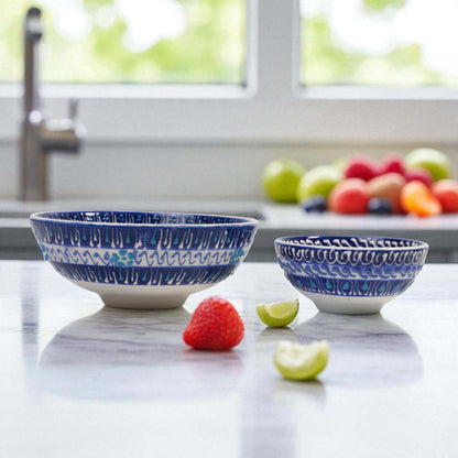 Two blue and white ceramic bowls on a kitchen counter with fruits in the background.