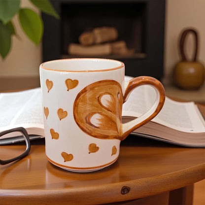 Mug with heart design on a wooden surface with a book and glasses in the background