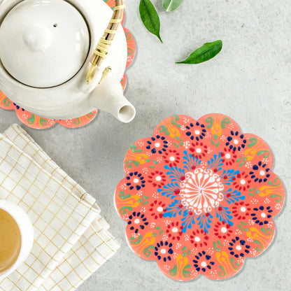 Colorful floral trivet on a gray surface with a teapot and cup.