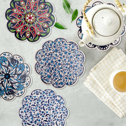 Decorative trivets with floral patterns on a table with a teapot and cup.