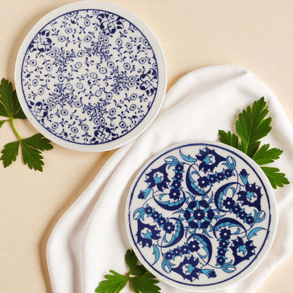 Two ceramic coasters with blue floral patterns on a beige background