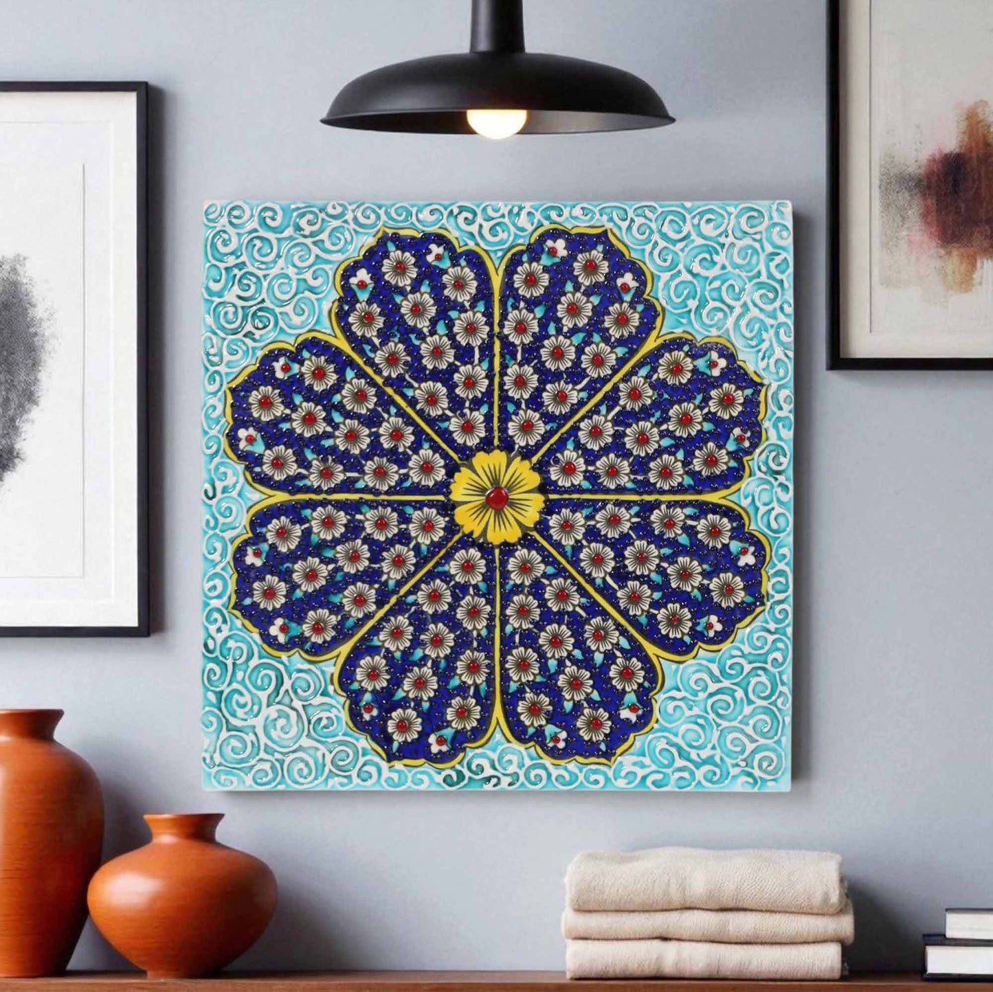 Decorative ceramic tile wall art with a floral pattern on a blue background, displayed in a room with vases and books.