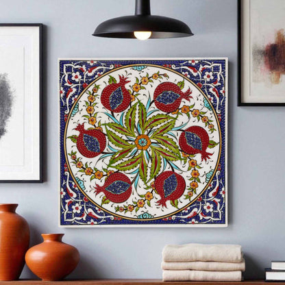 Decorative ceramic tile with floral and pomegranate design on a wall with vases and books below.