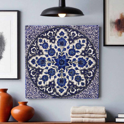 Decorative blue and white floral patterned ceramic tile on a gray wall with vases and books below.