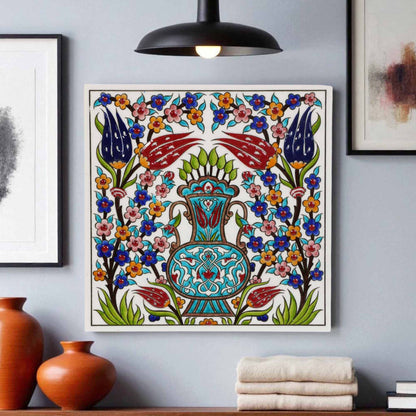 Decorative ceramic tile wall art with floral and chair design on a gray wall, with vases and books in the foreground.