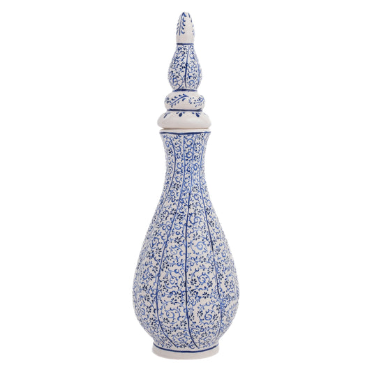 A tall, hand-painted Turkish ceramic vase with a white base and blue floral vine motif, featuring a pointed lid.