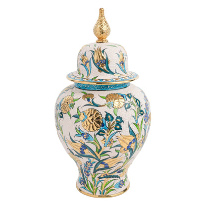 A hand-painted ceramic jar with a golden finial on the lid, featuring a blue and green floral motif with gold detailing.