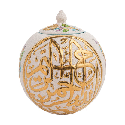 A spherical ceramic jar with hand-painted gold Islamic calligraphy and turquoise floral motifs, topped with a gilded lid finial.