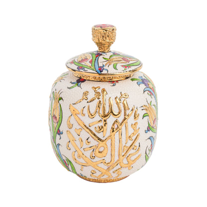 A handmade ceramic jar with a golden lid, featuring Arabic calligraphy and floral patterns in colors other than gold.