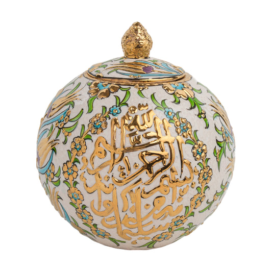 A spherical ceramic jar with gold Arabic calligraphy and floral patterns, featuring a golden finial on the lid.