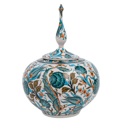 A bulbous ceramic decorative jar with a lid, featuring hand-painted teal blooms, stylized tulips, and leafy vines on a creamy white base.