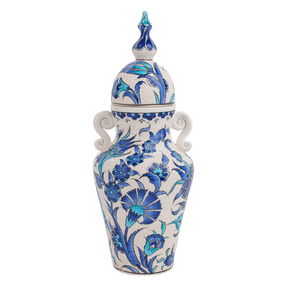 A hand-painted ceramic jar with a lid, featuring blue floral patterns and turquoise details, along with elegant side handles and a sculpted finial.