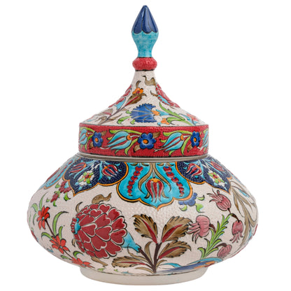 Hand-painted ceramic jar with a lid featuring a colorful floral pattern with red, blue, and green motifs on a white background, topped with a bold turquoise finial.