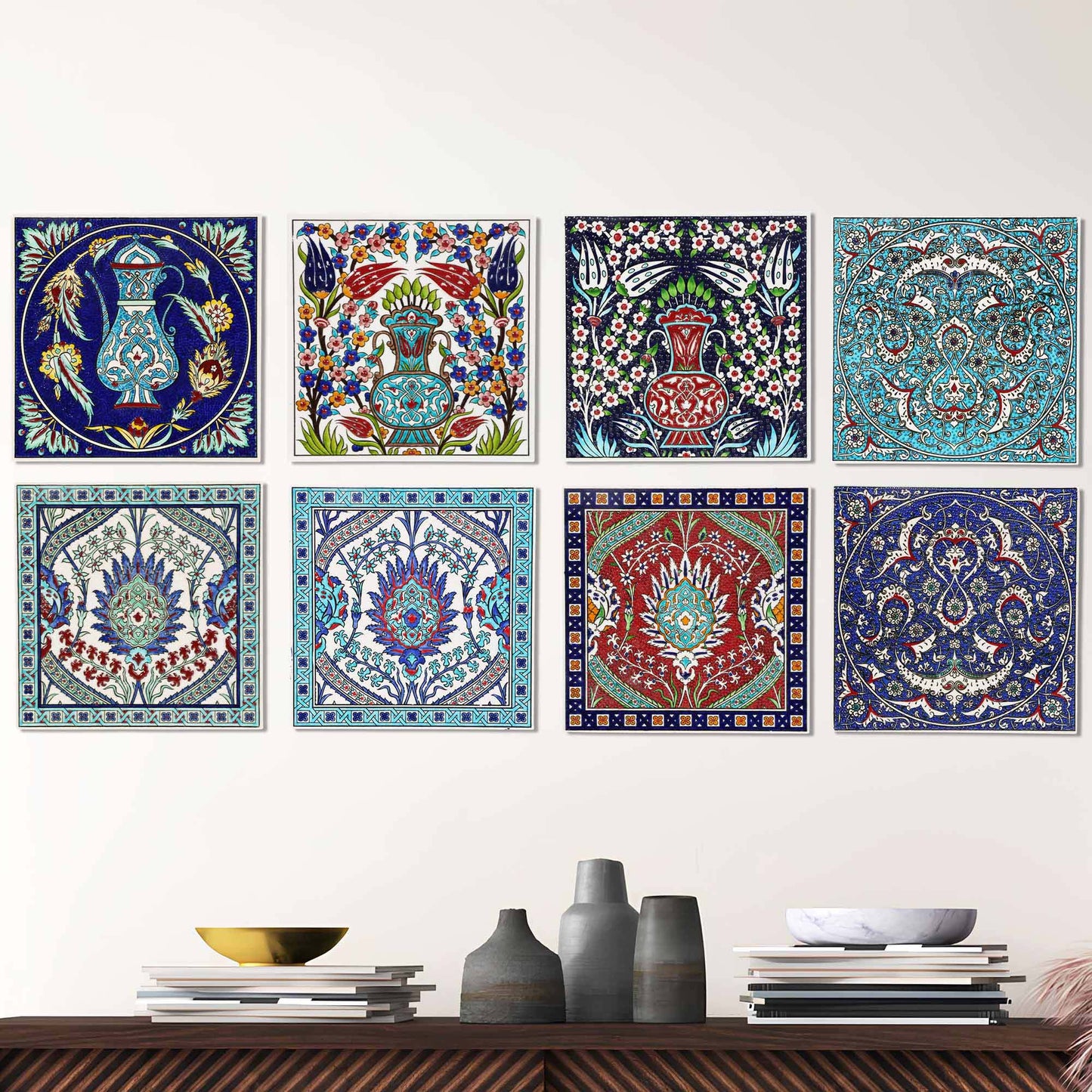 Set of colorful decorative ceramic tiles on a wall above a wooden shelf with vases and books.