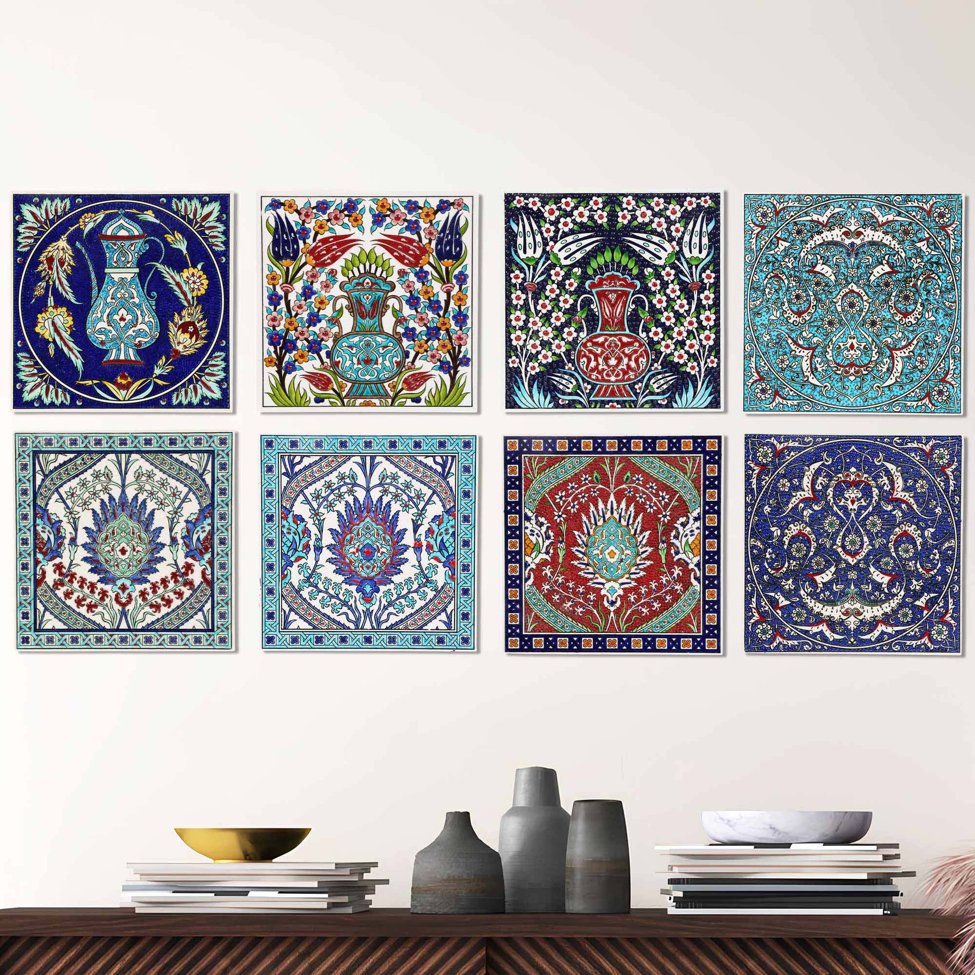 Set of colorful decorative ceramic tiles on a wall above a wooden shelf with vases and books.