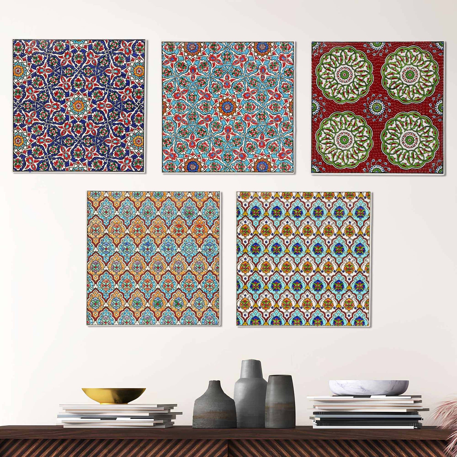Set of five colorful patterned ceramic tile wall art pieces on a white wall above a wooden shelf with decorative items.