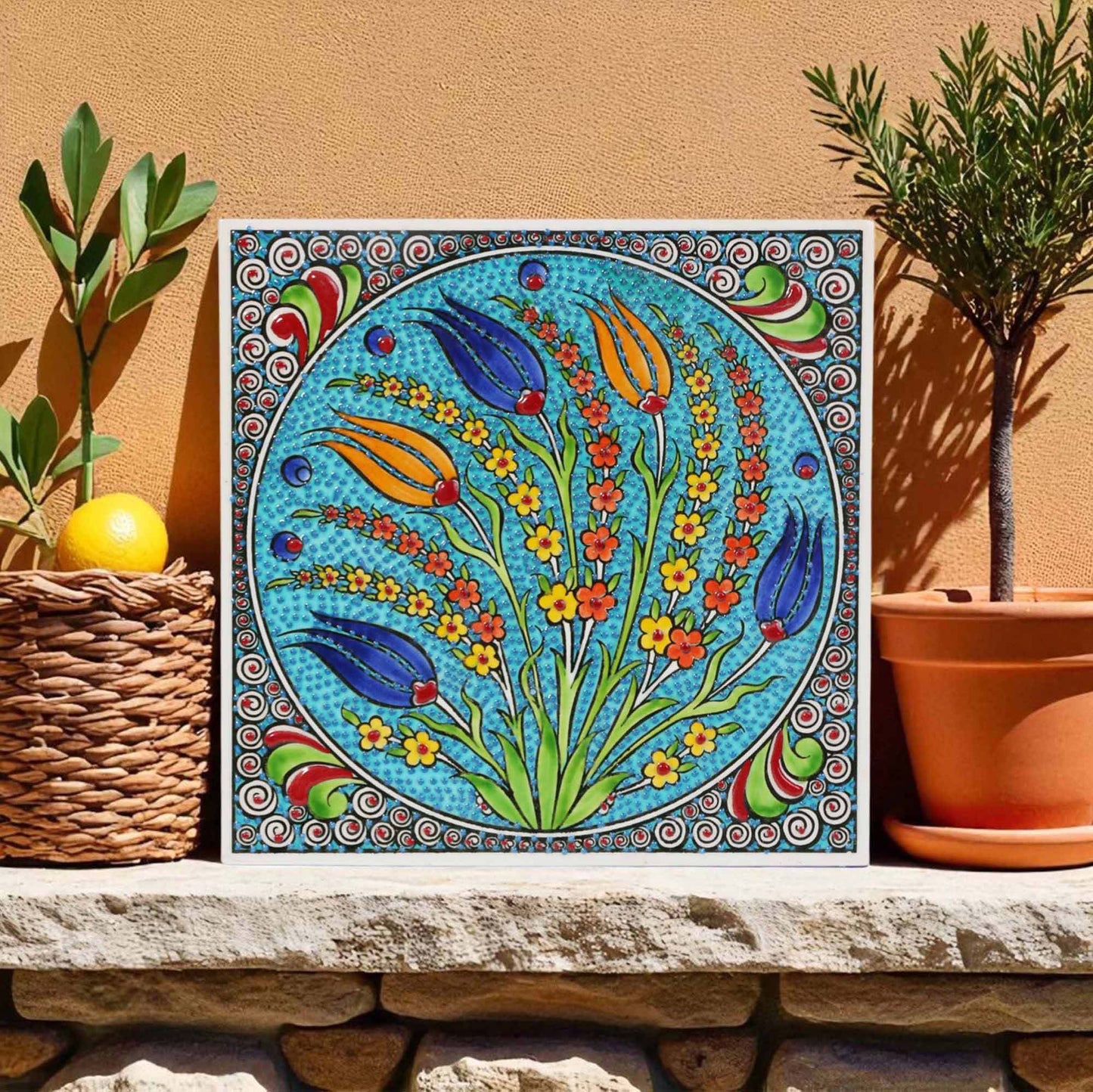 Colorful floral ceramic tile on a stone ledge with plants in the background