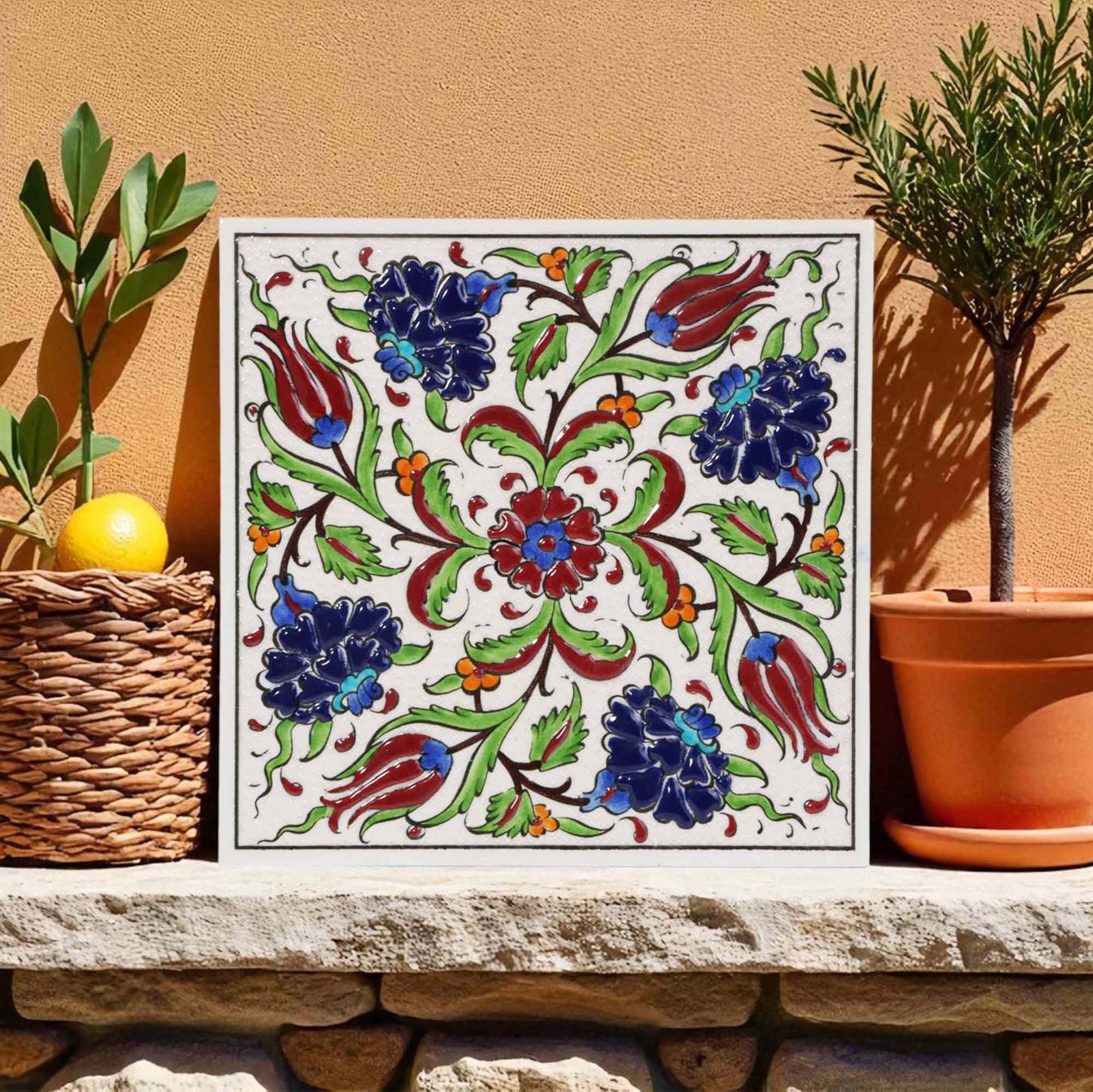 Decorative ceramic tile with floral pattern on a stone ledge with plants